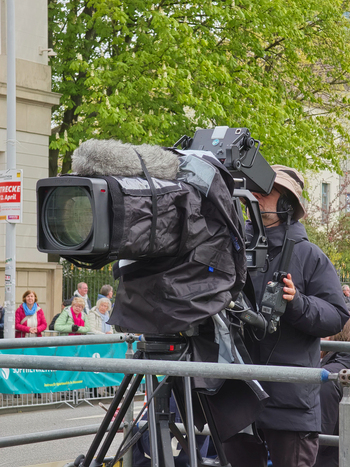 Hanover Germany 12 April 2026 View of a cameraman operating a professional broadcast camera on a tripod at a street event with spectators in the background.