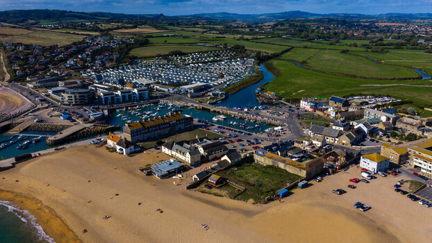 Aerial view of the harbour with boats sandy beach and coastal buildings in West Bay England United Kingdom. Aerial view of the harbour with boats sandy beach and coastal buildings in West Bay England United Kingdom.