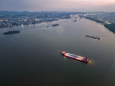 Aerial view of the Mahakam River with cargo ships and barges navigating the waterway near the city of Samarinda at dusk Samarinda East Kalimantan Indonesia. Aerial view of the Mahakam River with cargo ships and barges navigating the waterway near the city of Samarinda at dusk Samarinda East Kalimantan Indonesia.