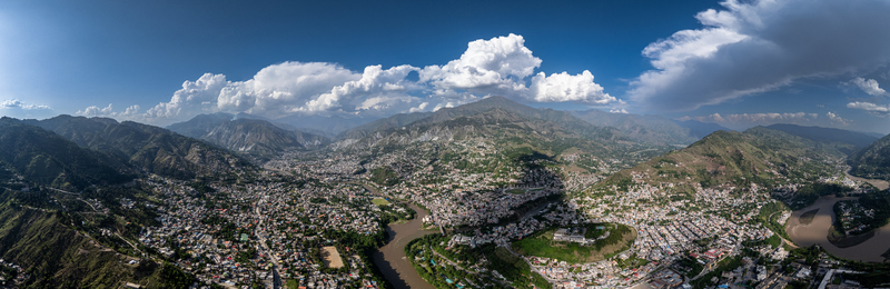 Aerial view of the confluence of the Jhelum and Neelum rivers surrounded by dense urban housing and dramatic mountain peaks in Muzaffarabad Azad Kashmir Pakistan. Aerial view of the confluence of the Jhelum and Neelum rivers surrounded by dense urban housing and dramatic mountain peaks in Muzaffarabad Azad Kashmir Pakistan.