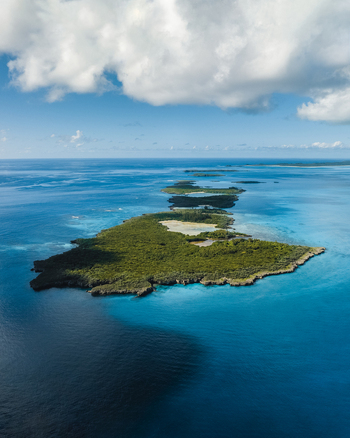 Aerial view of a vibrant verdant island surrounded by turquoise waters where the depths transition from light blues to deep indigos Ouvéa Loyalty Islands Province New Caledonia. Aerial view of a vibrant verdant island surrounded by turquoise waters where the depths transition from light blues to deep indigos Ouvéa Loyalty Islands Province New Caledonia.