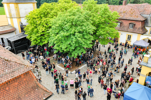 Aerial view of Schloss Jagersburg with a large crowd of people gathered in the courtyard under lush green trees in Eggolsheim Bayern Germany. Aerial view of Schloss Jagersburg with a large crowd of people gathered in the courtyard under lush green trees in Eggolsheim Bayern Germany.