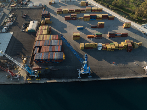 Aerial view of the container terminal with stacked shipping containers and large harbor cranes at the waterfront in Augusta Sicily Italy. Aerial view of the container terminal with stacked shipping containers and large harbor cranes at the waterfront in Augusta Sicily Italy.