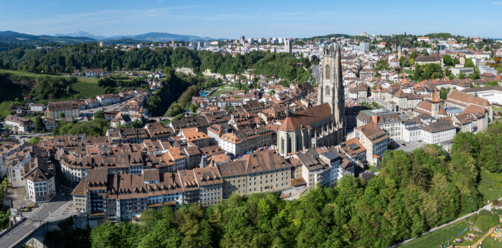 Aerial view of St Nicolas Cathedral surrounded by historic rooftops and lush green trees in Fribourg Fribourg Switzerland. Aerial view of St Nicolas Cathedral surrounded by historic rooftops and lush green trees in Fribourg Fribourg Switzerland.