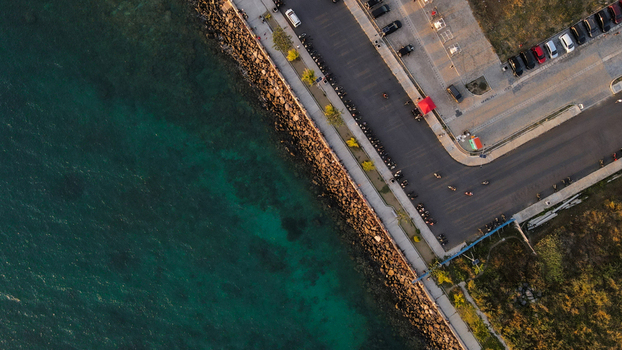 Aerial view of the coastal road and parking area in Sorong featuring turquoise sea rocky shoreline parked vehicles and golden hour sunlight in Sorong Southwest Papua Indonesia. Aerial view of the coastal road and parking area in Sorong featuring turquoise sea rocky shoreline parked vehicles and golden hour sunlight in Sorong Southwest Papua Indonesia.