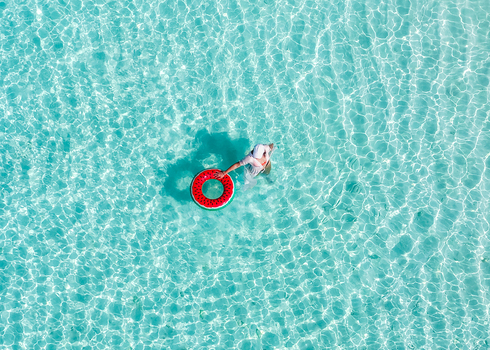 Aerial view of a person with a watermelon inflatable ring in crystal clear turquoise water Vashafaru Haa Alif Atoll Maldives. Aerial view of a person with a watermelon inflatable ring in crystal clear turquoise water Vashafaru Haa Alif Atoll Maldives.