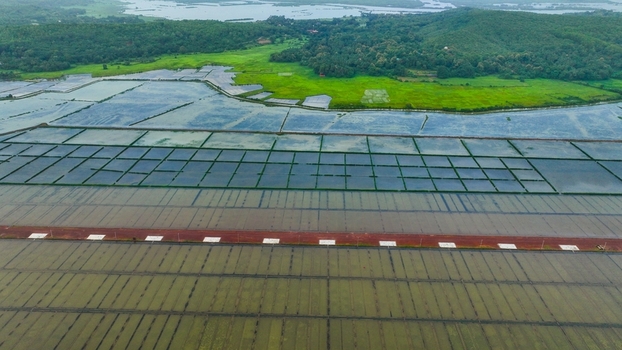 Aerial view of flooded paddy fields and agricultural land with lush green hills and water bodies in the background in Gokarna Karnataka India. Aerial view of flooded paddy fields and agricultural land with lush green hills and water bodies in the background in Gokarna Karnataka India.
