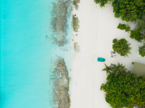 Aerial view of the turquoise waters meeting the pristine white sands of Vashafaru Island fringed by vibrant green vegetation Vashafaru Island Thiladhummathi Atoll Maldives. Aerial view of the turquoise waters meeting the pristine white sands of Vashafaru Island fringed by vibrant green vegetation Vashafaru Island Thiladhummathi Atoll Maldives.