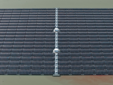 Aerial view of a large floating solar power plant on a lake with rows of dark photovoltaic panels and a central maintenance walkway in Dulmen North Rhine Westphalia Germany. Aerial view of a large floating solar power plant on a lake with rows of dark photovoltaic panels and a central maintenance walkway in Dulmen North Rhine Westphalia Germany.