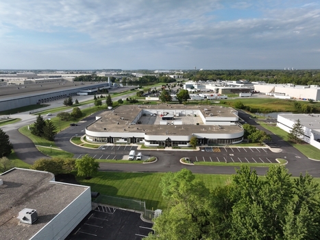 Aerial view of a modern commercial office building with a central courtyard surrounded by parking lots green lawns and industrial facilities in Indianapolis Indiana United States. Aerial view of a modern commercial office building with a central courtyard surrounded by parking lots green lawns and industrial facilities in Indianapolis Indiana United States.