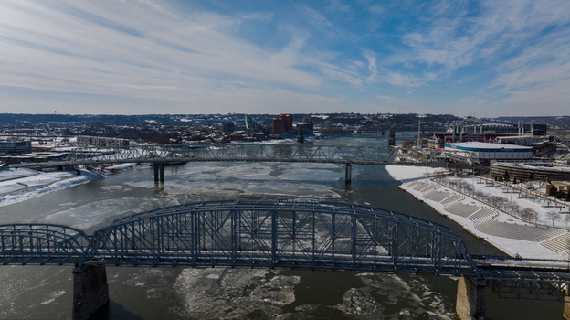 Aerial view of the Taylor Southgate Bridge and the icy Ohio River with snow covered banks and the city skyline under a blue sky in Cincinnati Ohio United States. Aerial view of the Taylor Southgate Bridge and the icy Ohio River with snow covered banks and the city skyline under a blue sky in Cincinnati Ohio United States.