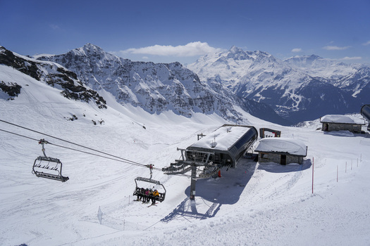 Aerial view of La Rosiere ski resort with chairlifts carrying skiers over snow covered slopes and majestic alpine peaks under a clear blue sky Montvalezan Auvergne Rhone Alpes France.