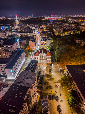 Aerial view of the historic Ostrogski Palace and modern city architecture illuminated at night with the National Stadium in the distance Warsaw Poland. Aerial view of the historic Ostrogski Palace and modern city architecture illuminated at night with the National Stadium in the distance Warsaw Poland.