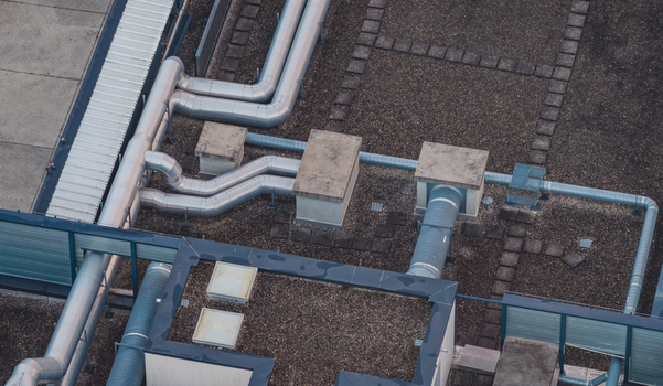 Aerial view of rooftop ventilation ducts exhaust shafts and mechanical HVAC infrastructure on a modern commercial building in Alixan Auvergne Rhone Alpes France.