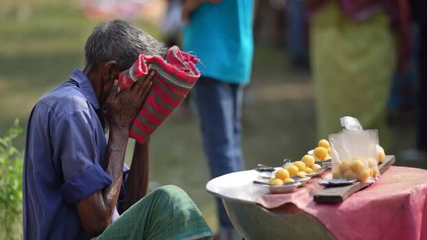 View of an elderly man covering his face by a food stall Bangladesh. View of an elderly man covering his face by a food stall Bangladesh.