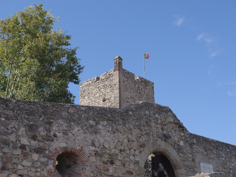 View of the historic stone walls and tower of Marvao Castle with a Portuguese flag flying against a clear blue sky in Marvao Portalegre District Portugal. View of the historic stone walls and tower of Marvao Castle with a Portuguese flag flying against a clear blue sky in Marvao Portalegre District Portugal.