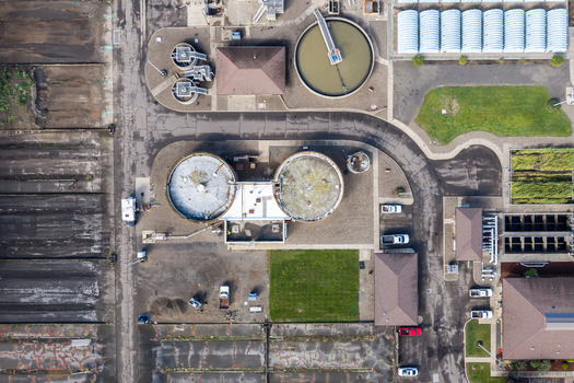 Aerial view of wastewater treatment plant featuring circular sedimentation tanks industrial buildings and surrounding green spaces in Woodburn Oregon United States. Aerial view of wastewater treatment plant featuring circular sedimentation tanks industrial buildings and surrounding green spaces in Woodburn Oregon United States.