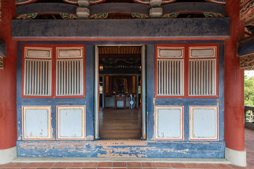 View of the traditional architecture of Chihkan Tower featuring ornate red pillars weathered blue wooden panels and slatted windows in Chihkan Village Tainan City Taiwan. View of the traditional architecture of Chihkan Tower featuring ornate red pillars weathered blue wooden panels and slatted windows in Chihkan Village Tainan City Taiwan.