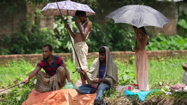 View of fishermen sitting on a riverbank with umbrellas Bangladesh.