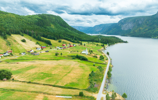 Aerial view of the village of Araksbo with its church green fields and a road running along the lake shore in Araksbo Agder Norway.