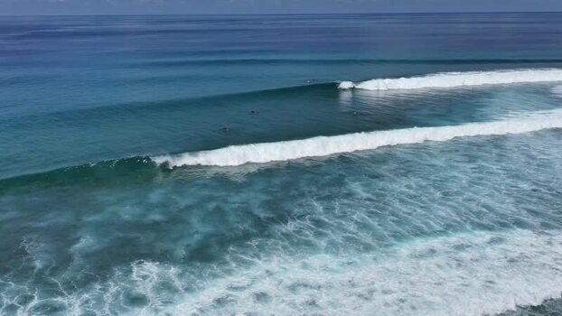 Aerial view of surfers riding waves in the turquoise ocean Maldives. Aerial view of surfers riding waves in the turquoise ocean Maldives.