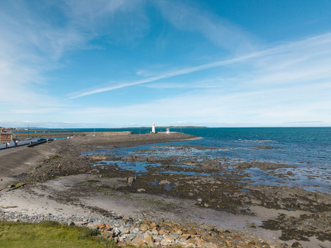 Aerial view of Donaghadee Harbour with its historic lighthouse rocky coastline and calm blue sea in Donaghadee Northern Ireland United Kingdom. Aerial view of Donaghadee Harbour with its historic lighthouse rocky coastline and calm blue sea in Donaghadee Northern Ireland United Kingdom.