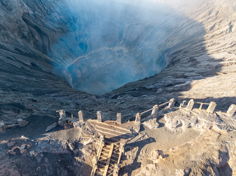 Aerial view of the Mount Bromo crater rim with stone stairs and railings overlooking the volcanic landscape in the morning light in Tosari East Java Indonesia.