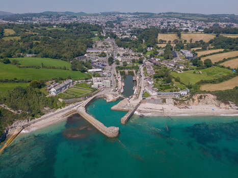 Aerial view of Charlestown Harbour with its historic stone piers surrounding village buildings green fields and turquoise coastal waters in Charlestown Cornwall United Kingdom. Aerial view of Charlestown Harbour with its historic stone piers surrounding village buildings green fields and turquoise coastal waters in Charlestown Cornwall United Kingdom.