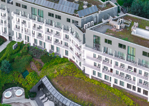 Aerial view of a modern hotel building featuring green roofs solar panels and outdoor hot tubs in Sopot Pomeranian Voivodeship Poland. Aerial view of a modern hotel building featuring green roofs solar panels and outdoor hot tubs in Sopot Pomeranian Voivodeship Poland.