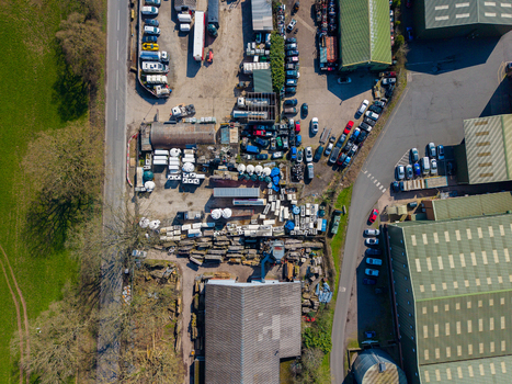 Aerial view of Ladfordfields Industrial Estate featuring industrial buildings rows of parked vehicles and outdoor storage areas surrounded by green fields in Stafford England United Kingdom. Aerial view of Ladfordfields Industrial Estate featuring industrial buildings rows of parked vehicles and outdoor storage areas surrounded by green fields in Stafford England United Kingdom.