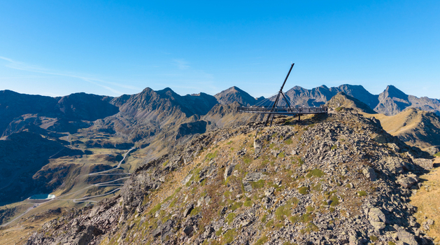 Aerial view of the Tristaina Sundial Balcony set on a rocky mountain peak overlooking a winding road in the valley under a clear blue sky Ordino Ordino Andorra.