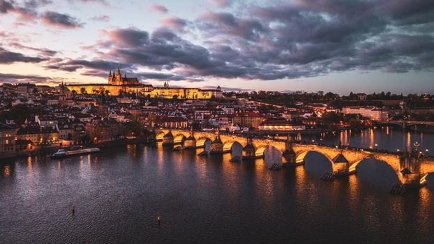 Aerial view of Prague Castle and Charles Bridge illuminated at dusk with the Vltava River flowing through the historic city center of Prague Prague Czechia. Aerial view of Prague Castle and Charles Bridge illuminated at dusk with the Vltava River flowing through the historic city center of Prague Prague Czechia.