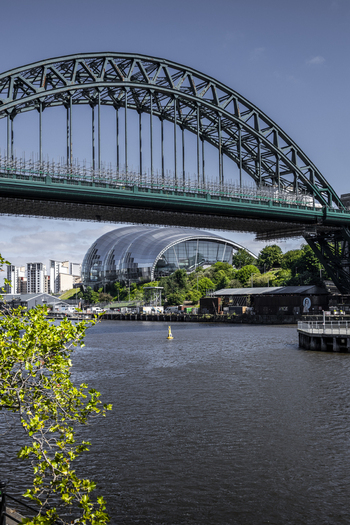 View of the iconic Tyne Bridge spanning the River Tyne with the modern Sage Gateshead concert hall in the background in Newcastle upon Tyne England United Kingdom. View of the iconic Tyne Bridge spanning the River Tyne with the modern Sage Gateshead concert hall in the background in Newcastle upon Tyne England United Kingdom.