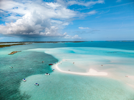 Aerial view of Man O War Cay Sandbar with small boats anchored in turquoise water under a blue sky in Rolletown Exuma The Bahamas. Aerial view of Man O War Cay Sandbar with small boats anchored in turquoise water under a blue sky in Rolletown Exuma The Bahamas.