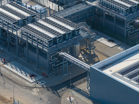 Aerial view of a modern data center facility featuring industrial cooling units complex piping systems and solar panels on the roof in The Netherlands. Aerial view of a modern data center facility featuring industrial cooling units complex piping systems and solar panels on the roof in The Netherlands.