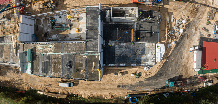 Aerial view of a construction site with building foundations concrete structures construction materials and heavy machinery in Latvia. Aerial view of a construction site with building foundations concrete structures construction materials and heavy machinery in Latvia.