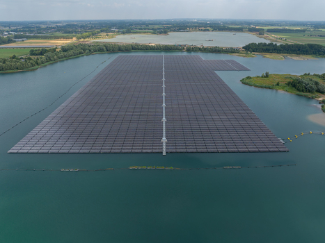 Aerial view of a large floating solar farm on a calm lake featuring rows of photovoltaic panels arranged on a platform surrounded by green landscape and water in the Netherlands. Aerial view of a large floating solar farm on a calm lake featuring rows of photovoltaic panels arranged on a platform surrounded by green landscape and water in the Netherlands.