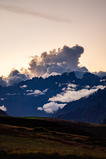 View of dramatic storm clouds over the rugged Andes mountains in the Sacred Valley at sunset with golden light illuminating the landscape in Urubamba Province Cusco Peru. View of dramatic storm clouds over the rugged Andes mountains in the Sacred Valley at sunset with golden light illuminating the landscape in Urubamba Province Cusco Peru.