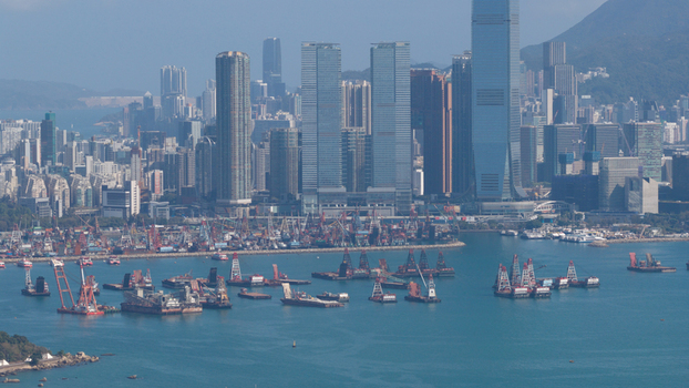 Aerial view of the dense West Kowloon skyline featuring the International Commerce Centre and cargo barges in the harbour on a clear day Hong Kong Hong Kong. Aerial view of the dense West Kowloon skyline featuring the International Commerce Centre and cargo barges in the harbour on a clear day Hong Kong Hong Kong.