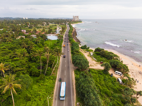 Aerial view of Dadalla beach and the coastal road lined with palm trees and vehicles under a cloudy sky in Galle Southern Province Sri Lanka. Aerial view of Dadalla beach and the coastal road lined with palm trees and vehicles under a cloudy sky in Galle Southern Province Sri Lanka.