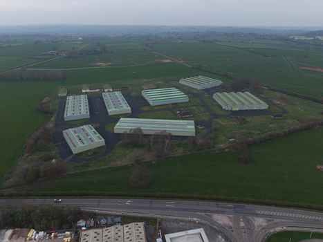 Aerial view of industrial buildings with silver roofs standing starkly against the green fields Market Drayton United Kingdom. Aerial view of industrial buildings with silver roofs standing starkly against the green fields Market Drayton United Kingdom.