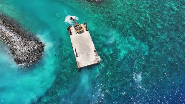 Aerial view of an excavator on a barge in turquoise waters Maldives. Aerial view of an excavator on a barge in turquoise waters Maldives.