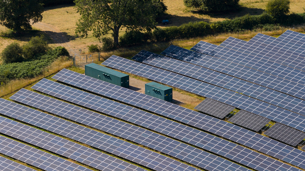 Aerial view of a large solar farm featuring rows of photovoltaic panels and green storage containers situated in a rural landscape in Atherstone England United Kingdom. Aerial view of a large solar farm featuring rows of photovoltaic panels and green storage containers situated in a rural landscape in Atherstone England United Kingdom.