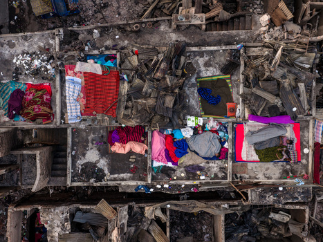 Aerial view of fire aftermath in Korail Basti showing charred structures debris and people resting on colorful blankets amidst the ruins in Dhaka Dhaka Division Bangladesh.