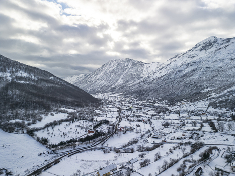 Aerial view of a snow covered village nestled in the valley of the Albanian Alps with winding roads and scattered houses surrounded by dramatic mountain peaks in Boge Shkoder County Albania. Aerial view of a snow covered village nestled in the valley of the Albanian Alps with winding roads and scattered houses surrounded by dramatic mountain peaks in Boge Shkoder County Albania.