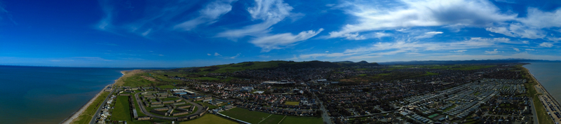 Aerial view of the coastline meeting the town with the vibrant blue sea contrasting against the green hills and the town of Prestatyn Prestatyn Wales United Kingdom. Aerial view of the coastline meeting the town with the vibrant blue sea contrasting against the green hills and the town of Prestatyn Prestatyn Wales United Kingdom.