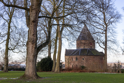 View of Sint Nicolaaskapel framed by tall bare trees in a park setting in Nijmegen Gelderland Netherlands. View of Sint Nicolaaskapel framed by tall bare trees in a park setting in Nijmegen Gelderland Netherlands.