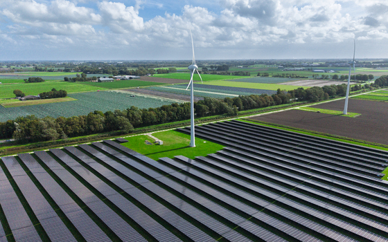 Aerial view of a solar farm with wind turbines set in the rural landscape of Warmenhuizen North Holland Netherlands.