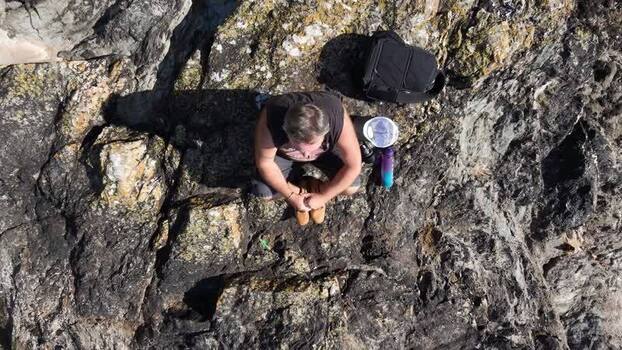 Aerial view of man on rocky outcrop in Fowey United Kingdom.
