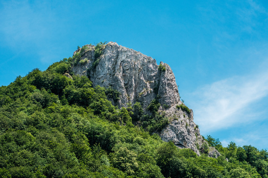 View of a rocky mountain peak covered with lush green forest under a clear blue sky in Savnik Savnik Municipality Montenegro. View of a rocky mountain peak covered with lush green forest under a clear blue sky in Savnik Savnik Municipality Montenegro.
